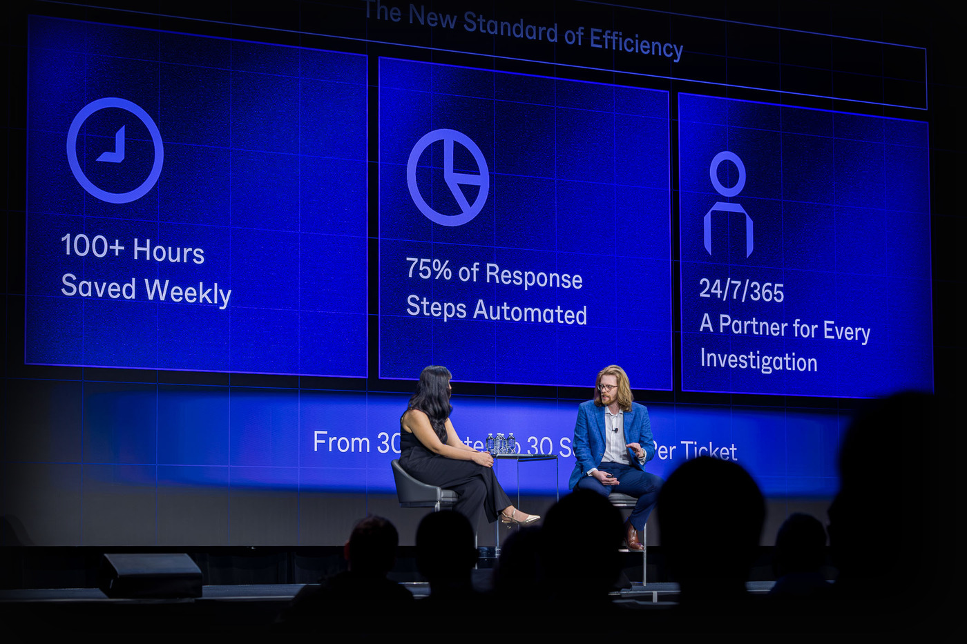 On stage beneath the efficiency metrics wall